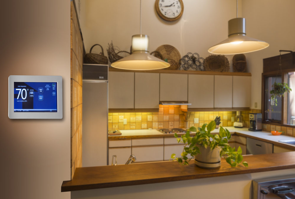 An outdated kitchen with white cabinets, yellow tile backsplash, and new smart thermostat on the wall to the left, displaying 70 degrees.