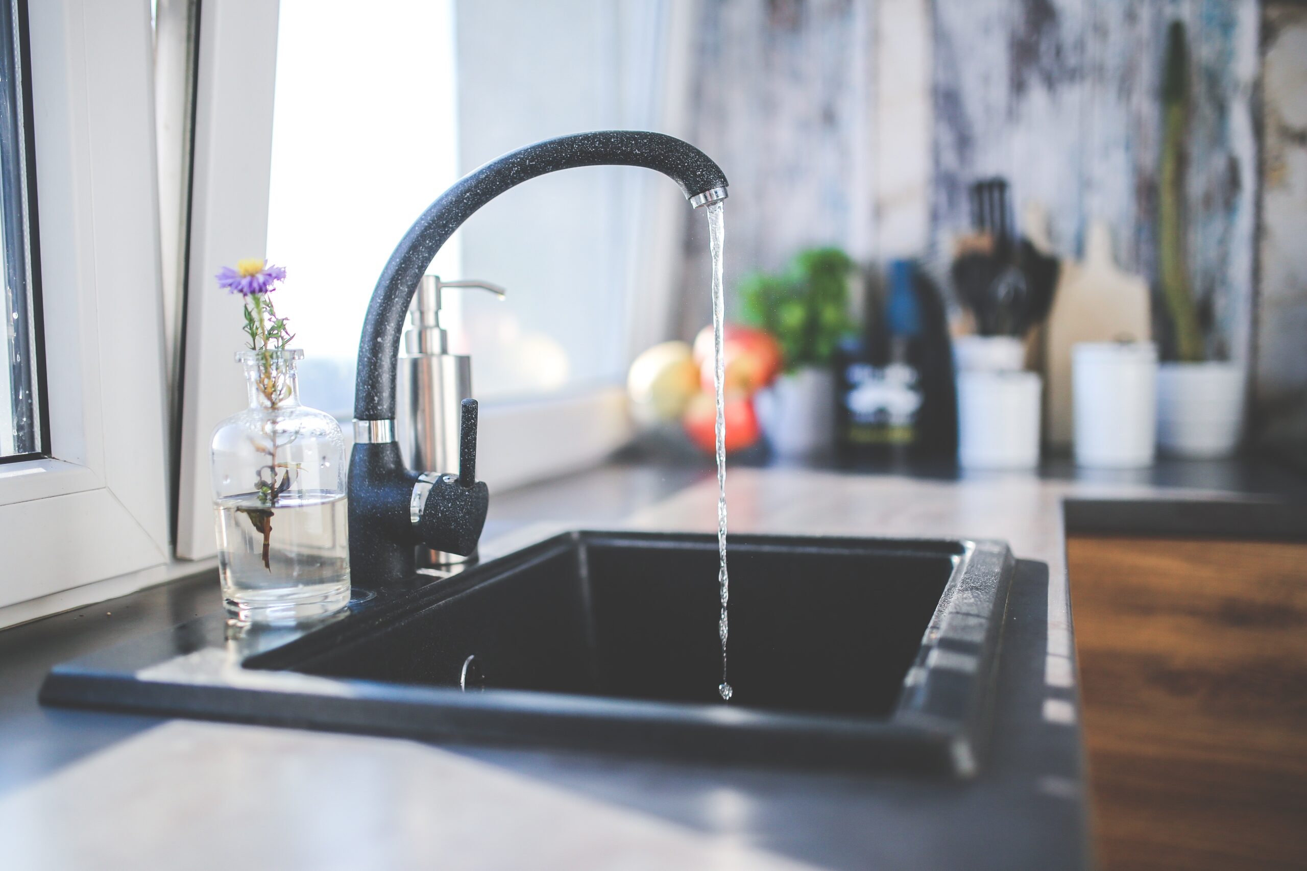 Water running from a faucet into a black kitchen sink