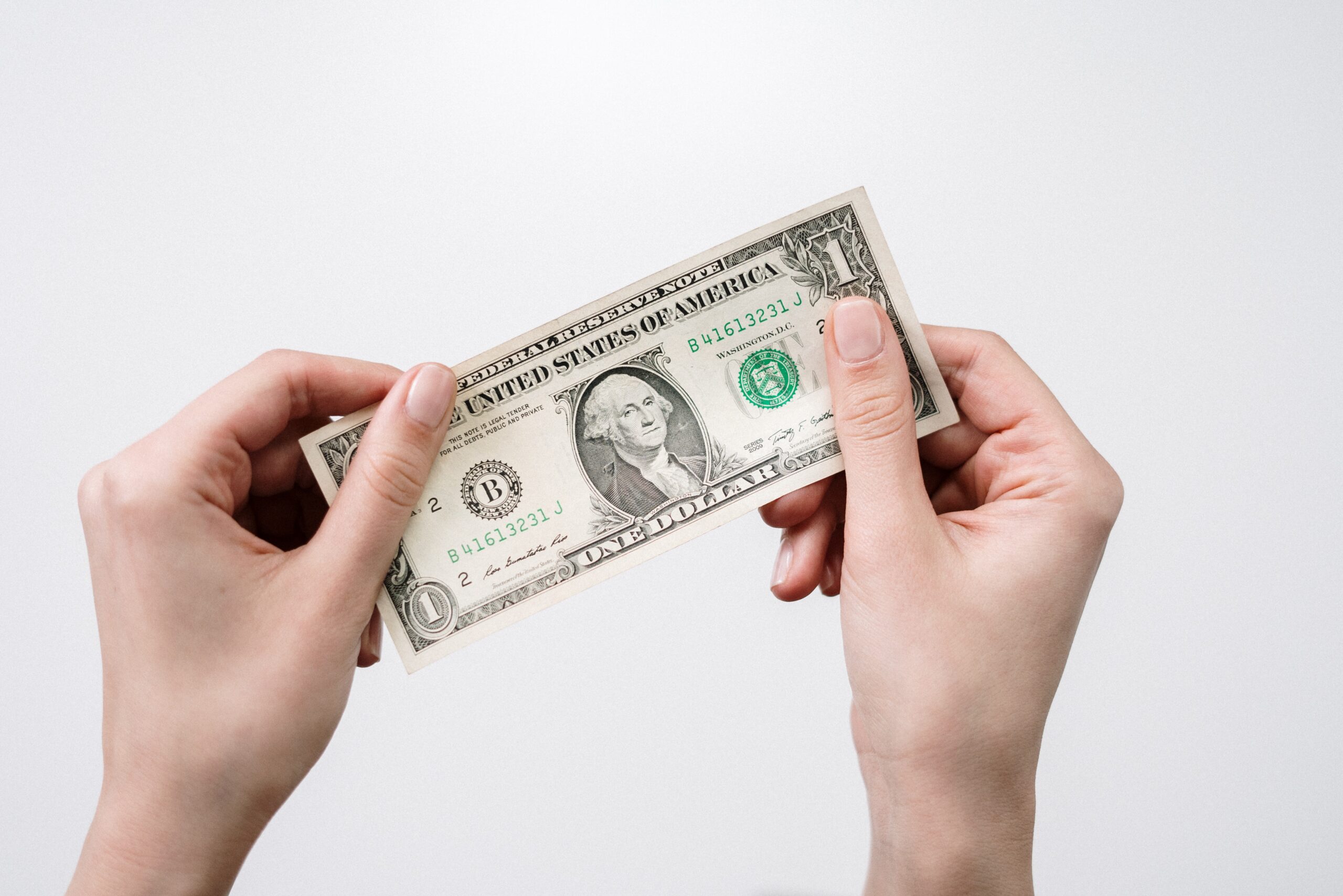 Two hands holding a dollar bill. White background.